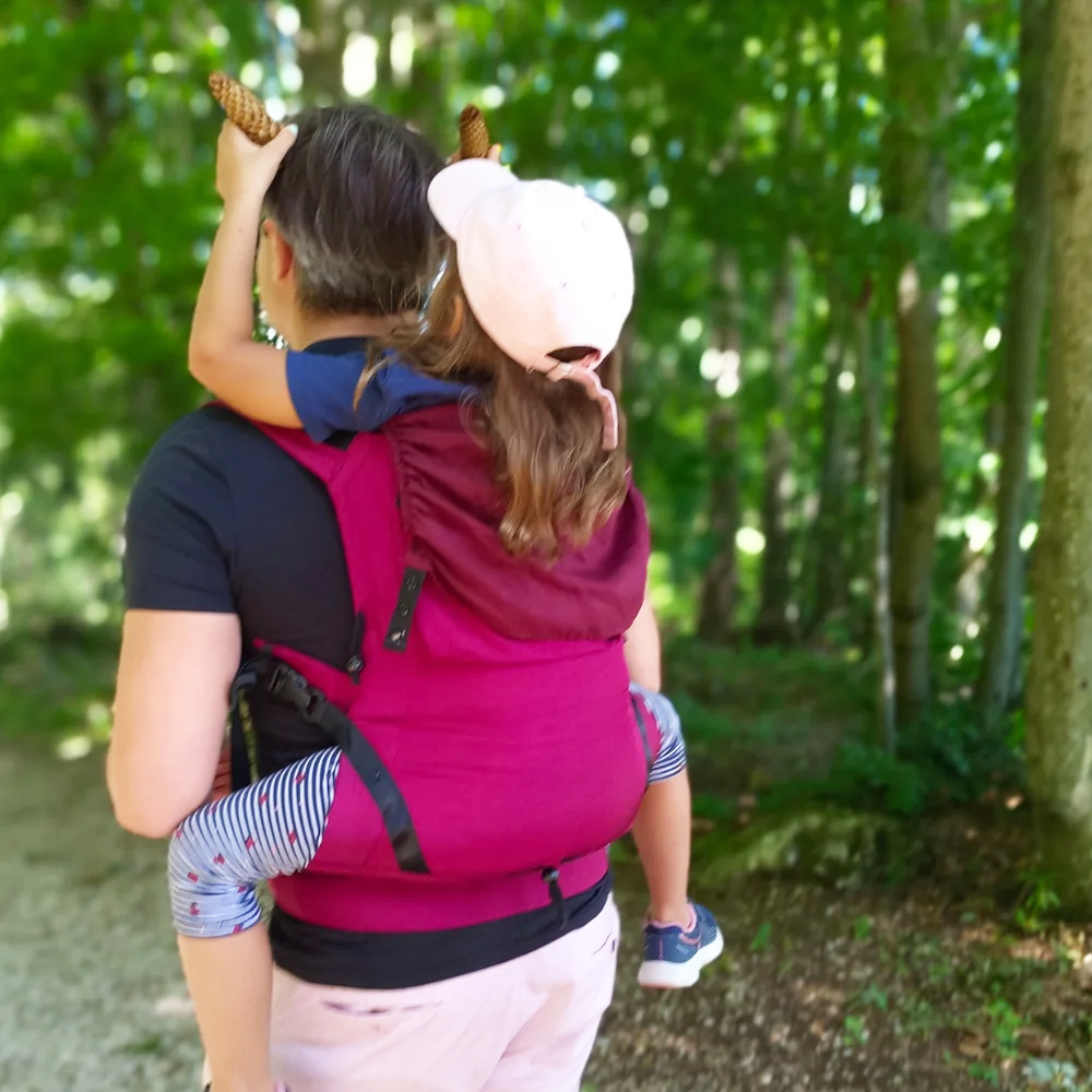 Kleinkind reicht seinen Eltern eine verpackte Leolin Babytrage aus Fallschirmseide