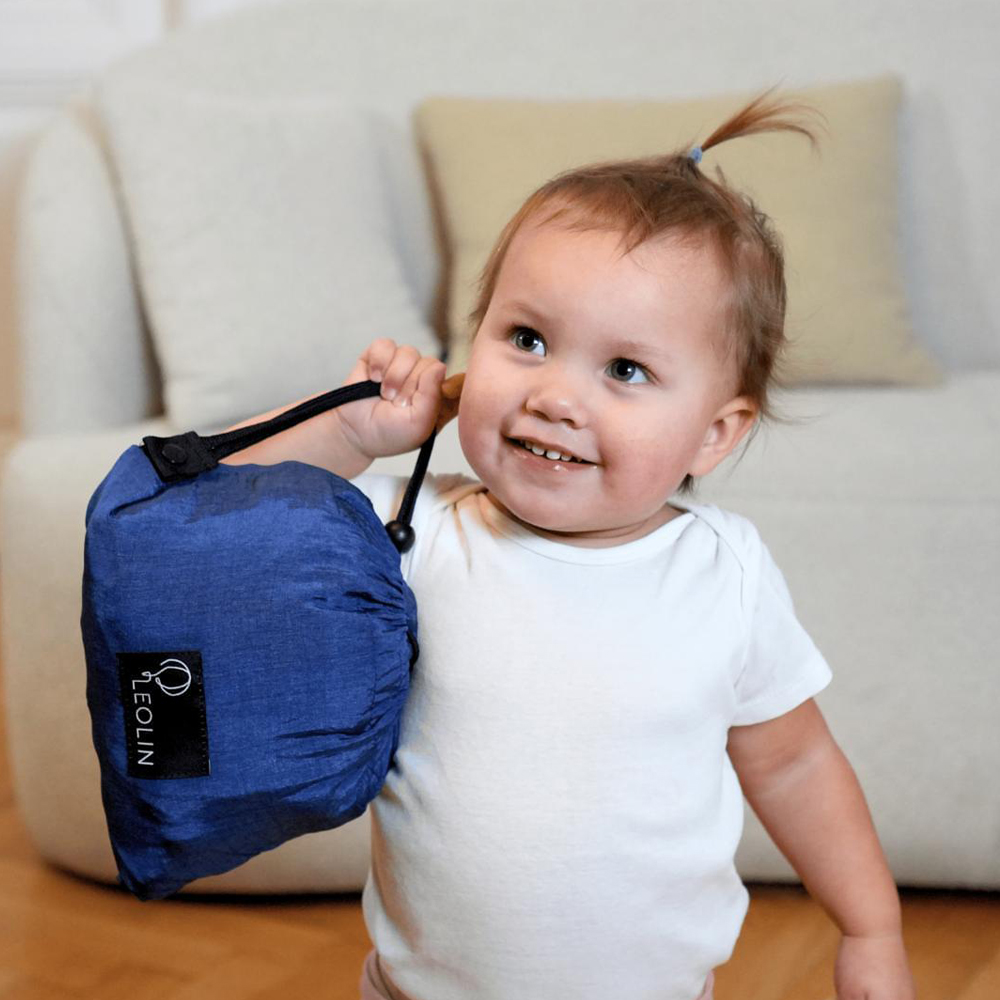 Kleinkind reicht seinen Eltern eine verpackte Leolin Babytrage aus Fallschirmseide
