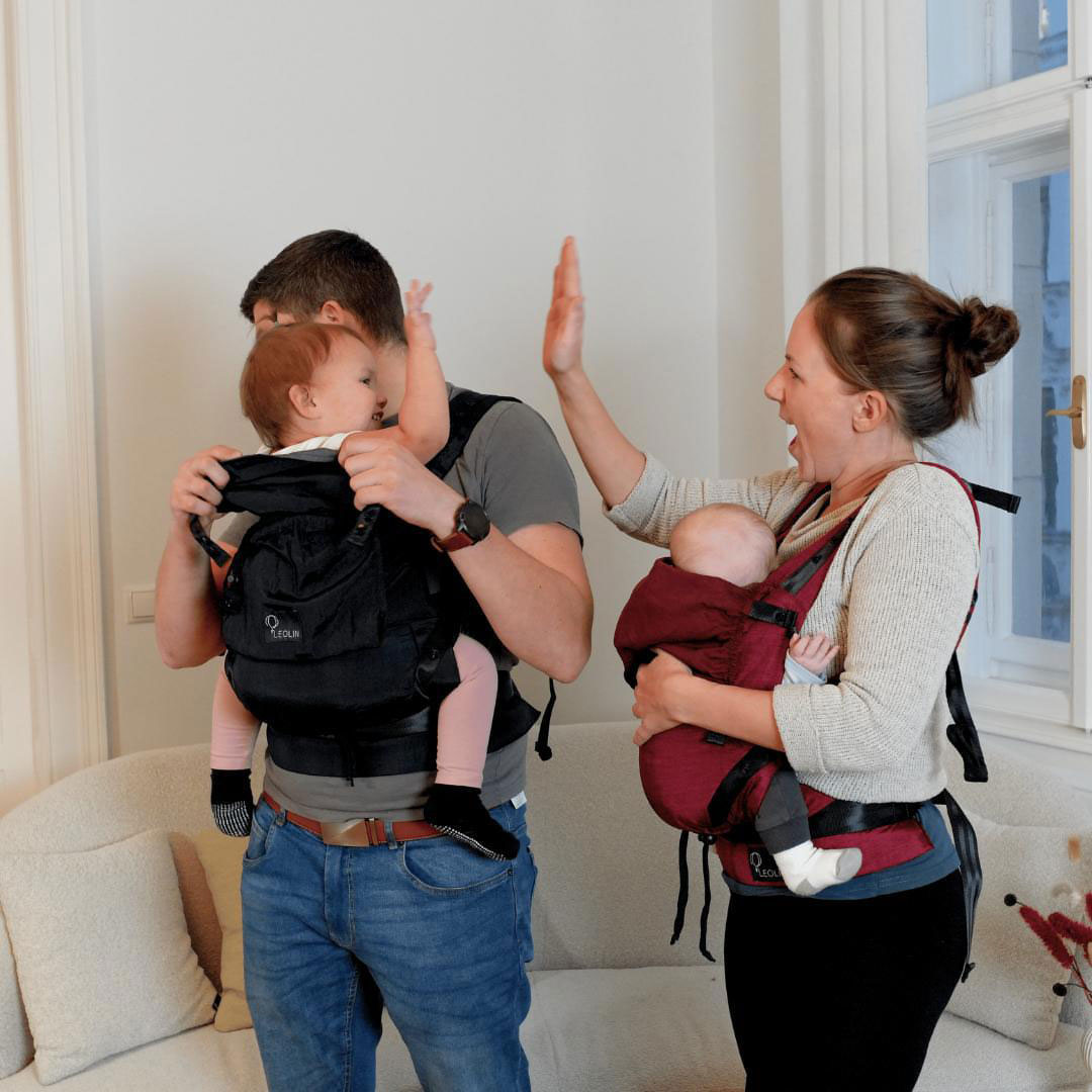 Kleinkind reicht seinen Eltern eine verpackte Leolin Babytrage aus Fallschirmseide